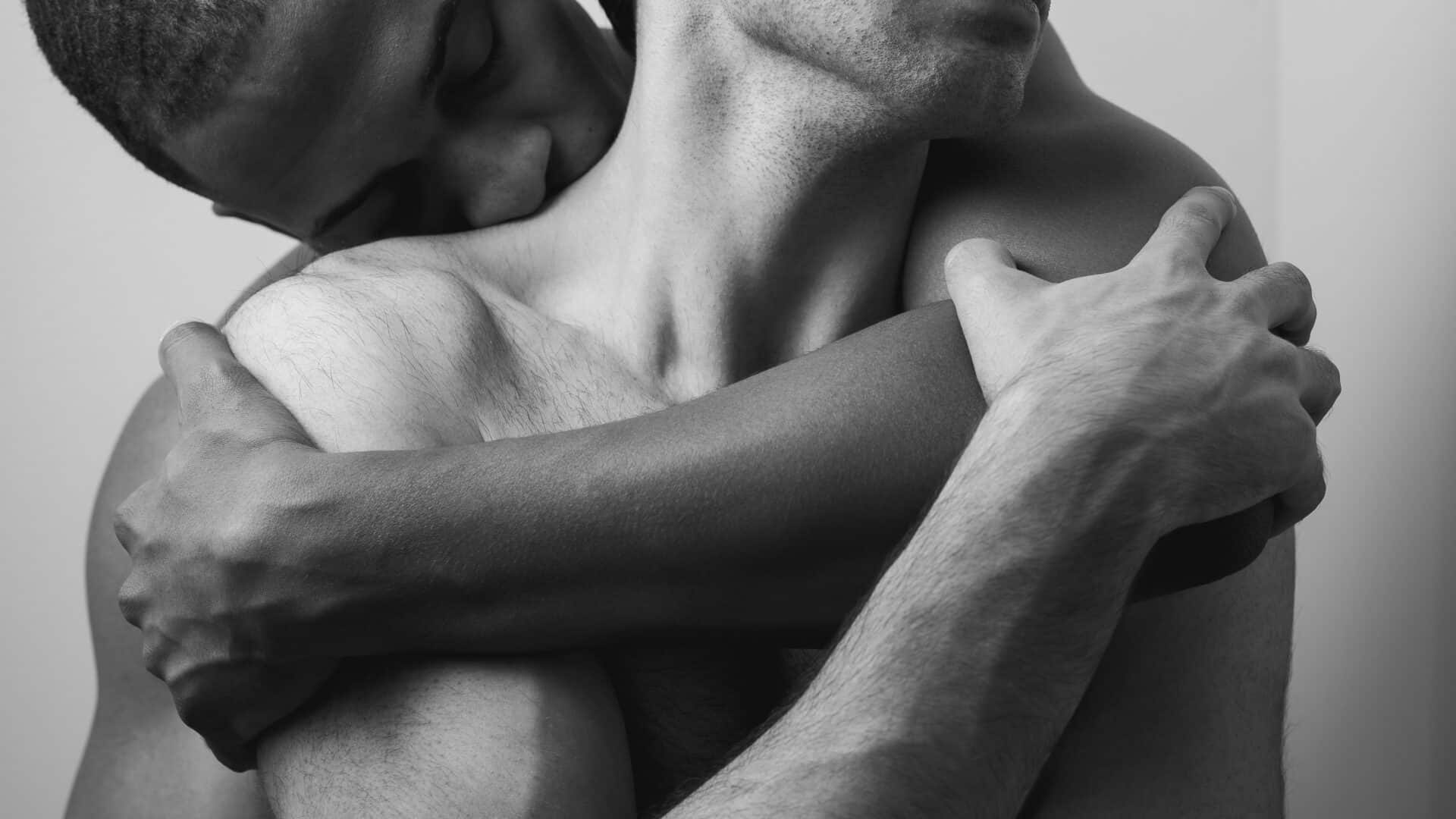 Das Foto zeigt ein schwules Paar in schwarz-weiß, eng umschlungen. Foto von Aaron Barrera / Unsplash